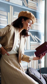 A lady wears a blazer and a pleated skirt.